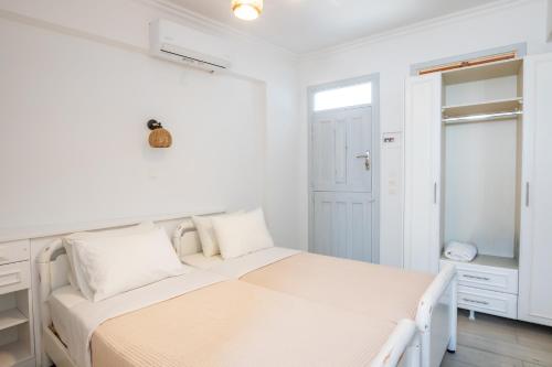 a white bedroom with a bed and a closet at Zorbas Studios in Lefkos Karpathou