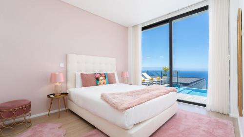 a white bedroom with a large bed and a balcony at Villa Lilian by LovelyStay in Arco da Calheta