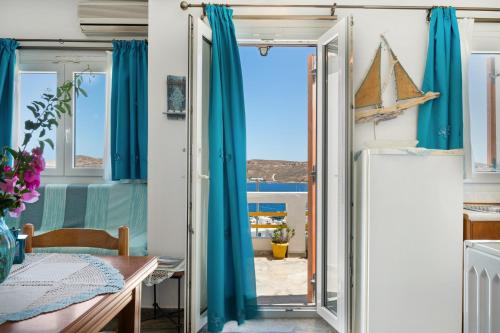 a room with blue curtains and a table and a window at Agnadi Studio in Serifos Chora