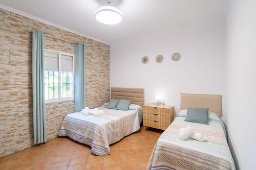 a bedroom with two beds and a brick wall at Casa Rural Villa Manantial in La Puebla de Cazalla
