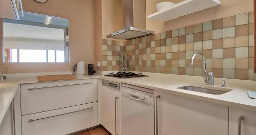 a kitchen with white cabinets and a sink at Exclusive Position Front Line Apartments Calau in Calella de Palafrugell