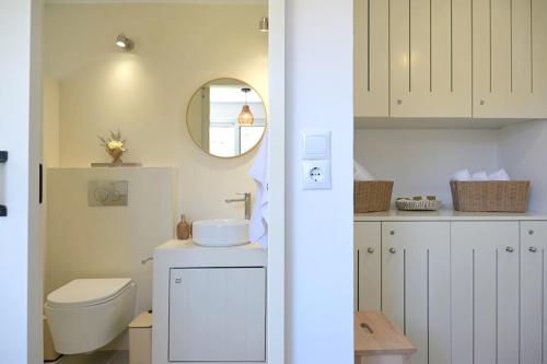 a white bathroom with a toilet and a mirror at MarGo House Kythnos in Kithnos
