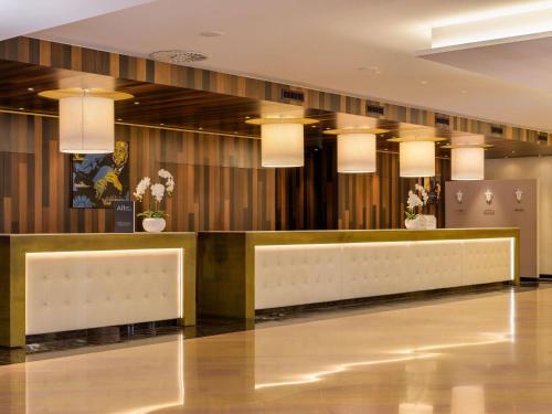 a lobby with a reception desk and pendant lights at Mövenpick Hotel Geneva in Geneva