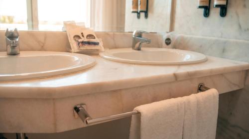 two sinks in a bathroom with two towels at Hotel Vértice Chipiona Mar in Chipiona