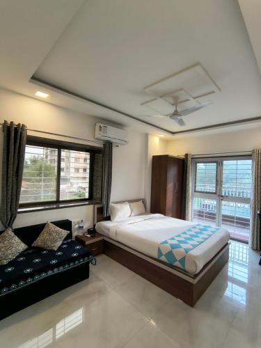 a bedroom with a bed and a couch and windows at Stay Origin, In Nashik in Nashik