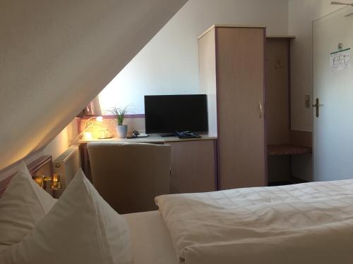 a bedroom with a bed and a desk with a computer at Hotel & Restaurant Park Cafe ISA in Erfurt