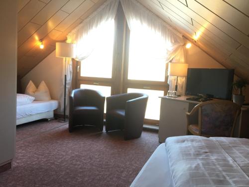 ein Schlafzimmer mit einem Bett, 2 Stühlen und einem TV in der Unterkunft Hotel & Restaurant Park Cafe ISA in Erfurt