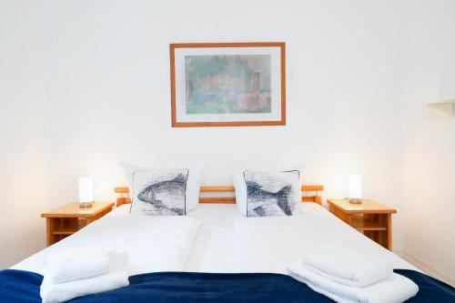 a bedroom with a bed with white sheets and a painting at Ort Lemkenhafen Sundbrise in Fehmarn