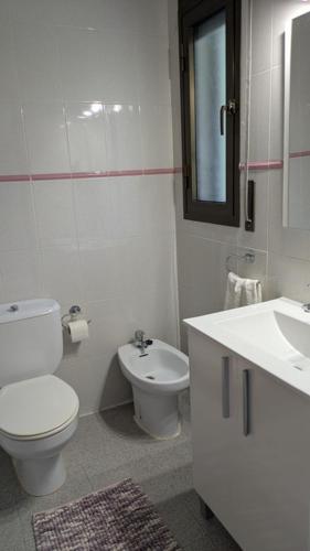 a white bathroom with a toilet and a sink at Gaviotas piscina comunitaria in Calafat