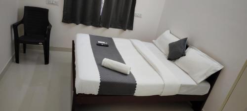 a bed with a black and white comforter and a chair at Twin Tag Residency in Chennai