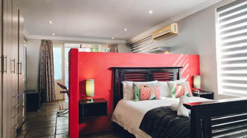 a bed with a red headboard in a room at 314 on Clark Guest House in Pretoria