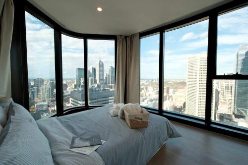 a bedroom with a white bed and large windows at Premium 3BR CBD Apt Prime Location in Melbourne