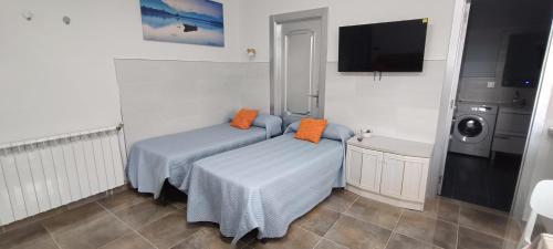two beds in a room with a tv and a washing machine at MariaS Vacation Rental in Obregón
