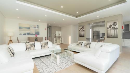 a living room with white couches and a table at Evoque Villa by LovelyStay in Arco da Calheta