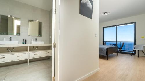 a bathroom with two sinks and a view of the ocean at Evoque Villa by LovelyStay in Arco da Calheta