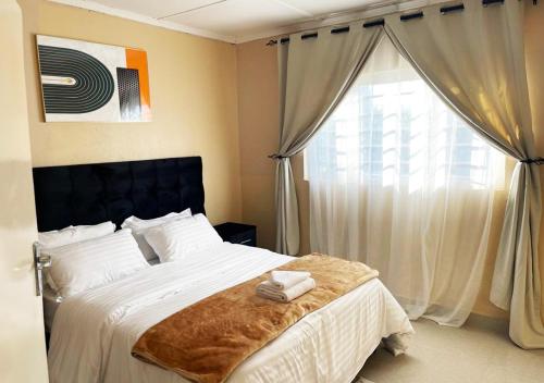 a bedroom with a bed with white sheets and a window at Sofies's Apartments in Lusaka