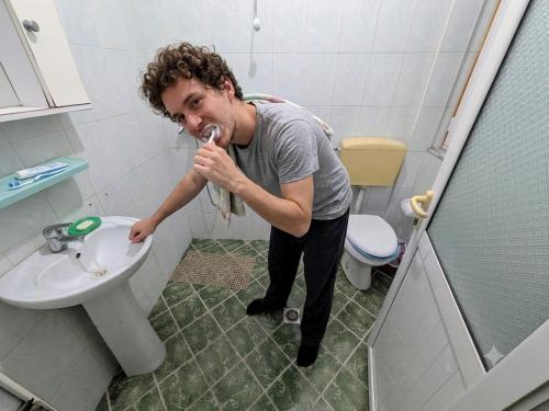 a man standing in a bathroom brushing his teeth at Adventure Beach Hostal in Durrës