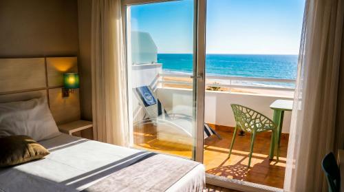 a bedroom with a bed and a view of the ocean at Hotel Vértice Chipiona Mar in Chipiona