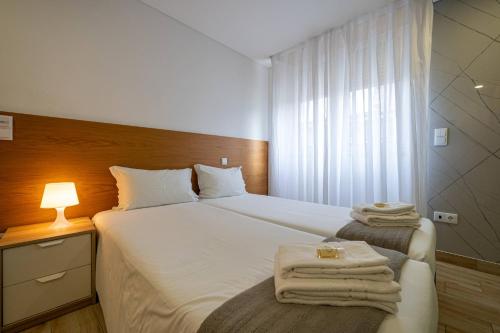 a bedroom with a bed with towels on it at Central Suítes 1 in São João da Madeira