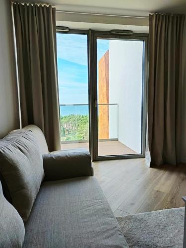 a room with a couch and a large window at Pinea Apartments in Pobierowo