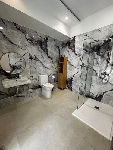 a bathroom with a stone wall with a toilet and a sink at Central Hostel Malta in Birkirkara