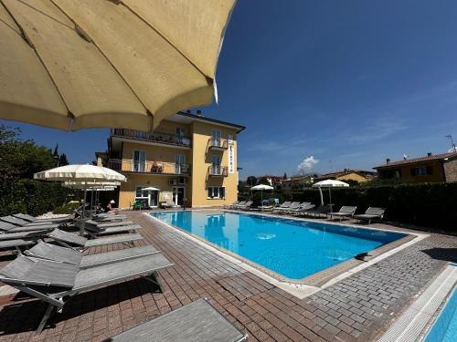 ein Schwimmbad mit Liegestühlen und Sonnenschirmen neben einem Gebäude in der Unterkunft Residence Beatrix in Bardolino