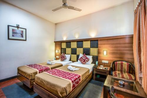 a hotel room with two beds and a chair at Abirami Residency in Pondicherry