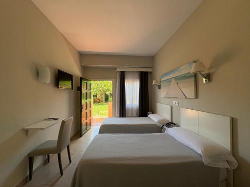 a hotel room with three beds and a desk at Hotel Los Jazmines in Torremolinos