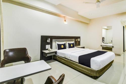 a bedroom with a bed and a desk and a chair at Hotel O New Pride in Sāngli