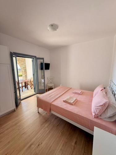 a bedroom with a large bed with pink sheets at Rosalie Home - Open Sea Duo in Tinos
