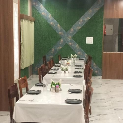 a group of tables with white tablecloths and chairs at Hotel ashtha inn in Gaya