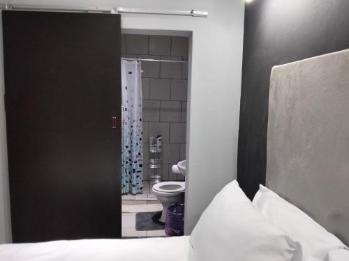 a bedroom with a bed and a bathroom with a toilet at Sunflower Acres in Kimberley