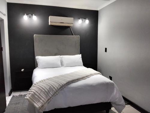 a bedroom with a white bed with a black wall at Sunflower Acres in Kimberley