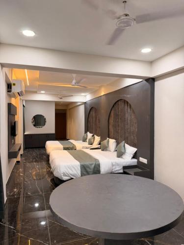 a hotel room with three beds and a table at Hotel J K Town in Ahmedabad