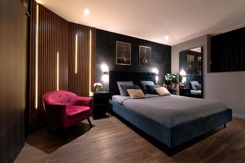 a bedroom with a bed and a pink chair at Love Room Lorient - Le King Size - Balnéo 2 places in Lorient