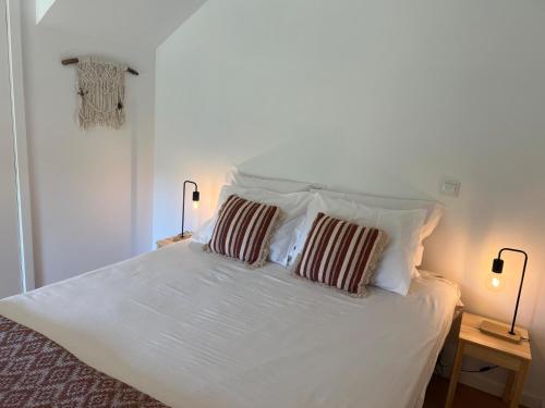 a white bed with two pillows on top of it at Refúgio do Saltadouro - Entre o Gerês e a Cabreira in Ruivãis