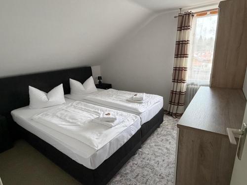 a bedroom with a bed with white sheets and a window at Alpenblick am Kienberg in Pfronten