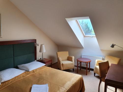 a bedroom with a bed and chairs and a window at Dwór Zielone Wzgórza in Bukowno