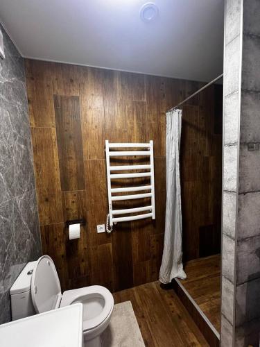 a bathroom with a toilet and a wooden wall at Апартаменти La Familia в Одеський Бульвар - Od 433 in Teremki