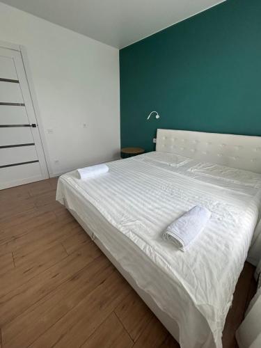 a bedroom with a white bed with a green wall at Апартаменти La Familia в Одеський Бульвар - Od 433 in Teremki