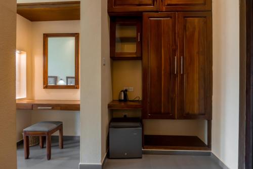 a kitchen with wooden cabinets and a trash can at Paddyway Resort in Arugam Bay