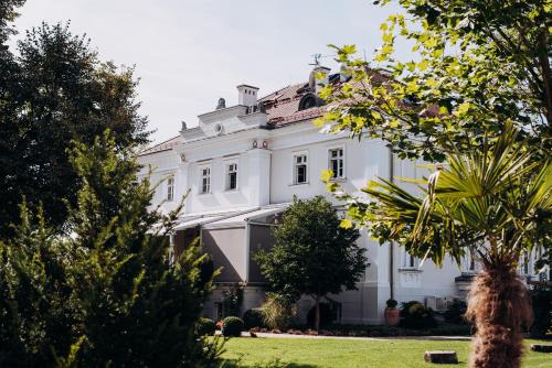 a white house with trees in the foreground at Hotel Jakubus in Wilków