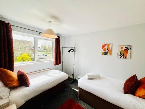a bedroom with two beds and a window at Bright & Sociable Home with Garden Retreat in Capel Saint Mary