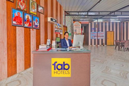 a woman is standing at a table with a laptop at FabHotel Shree Ram Aadhar 900 Mtr from Ram mandir in Ayodhya