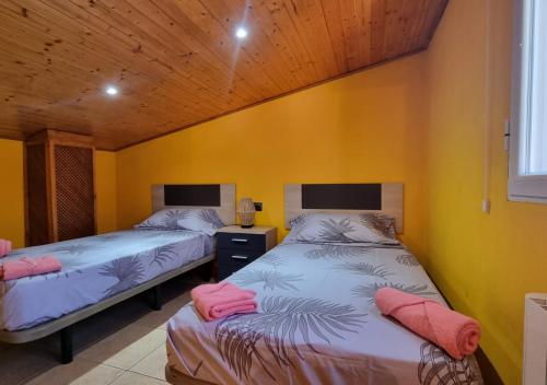 two beds in a room with yellow walls at Areatza Home Mountain in Santiago de la Espada