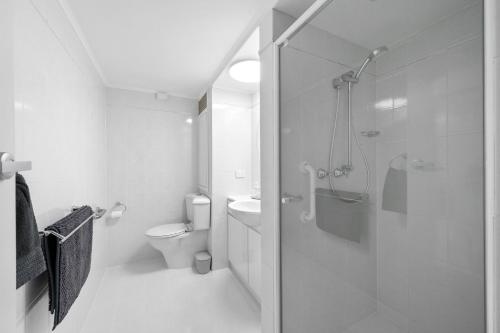 a white bathroom with a shower and a toilet at Central Freo Hideaway in Fremantle