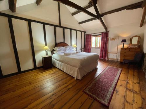 a bedroom with a large bed and a wooden floor at 16th Century Devon Farmhouse Stunning Views in Winkleigh