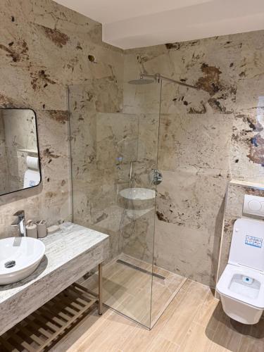 a bathroom with a glass shower and a toilet at Dengu Luxury Apartments in Golem