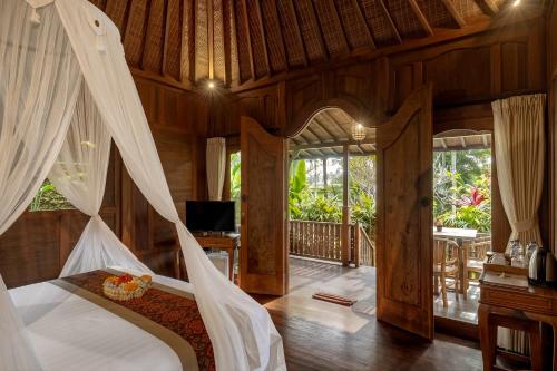 a bedroom with a bed with a canopy at KERAMAN SUITE UBUD in Ubud