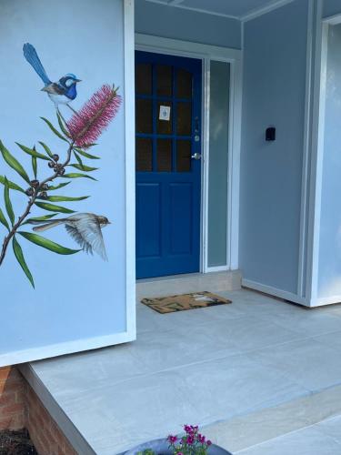 a blue door with a bird sitting on a plant at The Blue Wren in Blackheath